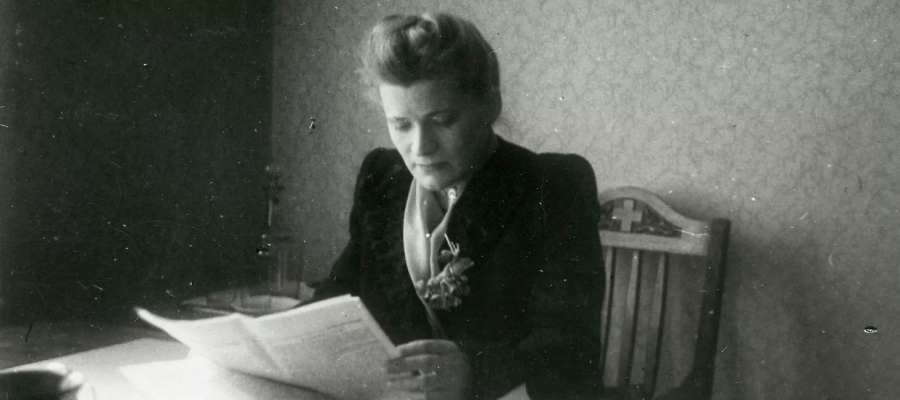 Herta Hanzena sēžot un lasot avīzi