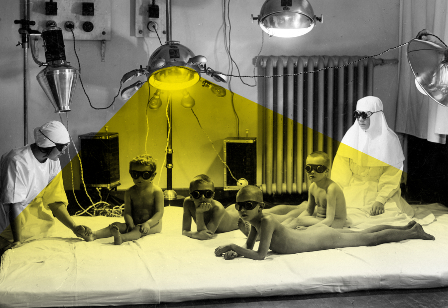 Naked children basking under an artificial solar apparatus, with large black glasses and with both doctors at either end.